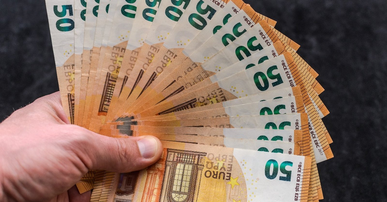 Eine Hand hält einen Fächer aus 50-Euro-Scheinen.