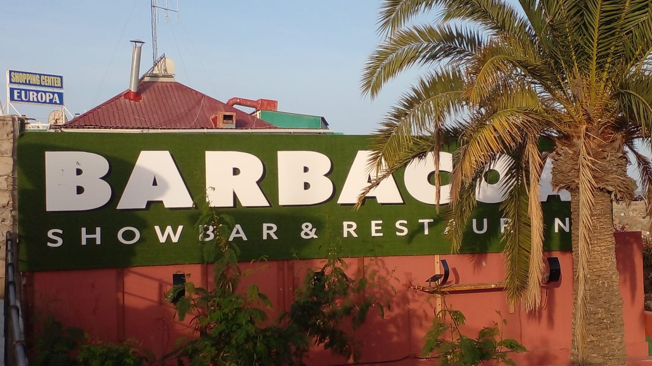 Das grosse grüne BARBACOA-Showbar-Schild über der roten Fassade, daneben eine Palme