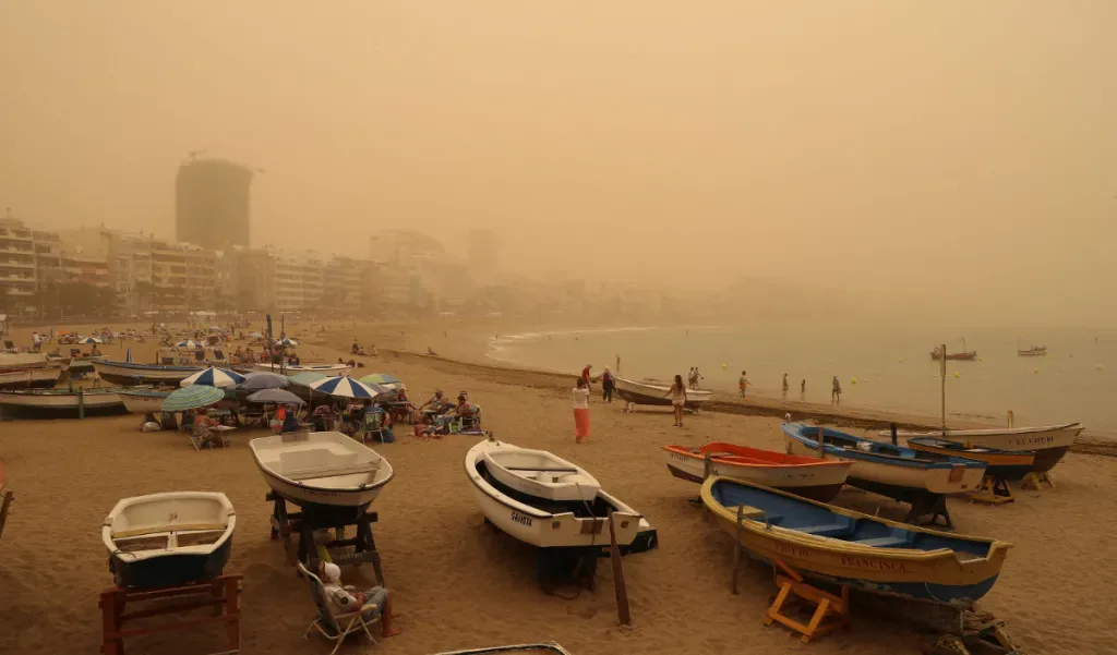 La spiaggia di Las Canteras a Las Palmas de Gran Canaria avvolta dalla foschia gialla di una calima, con barche in primo piano