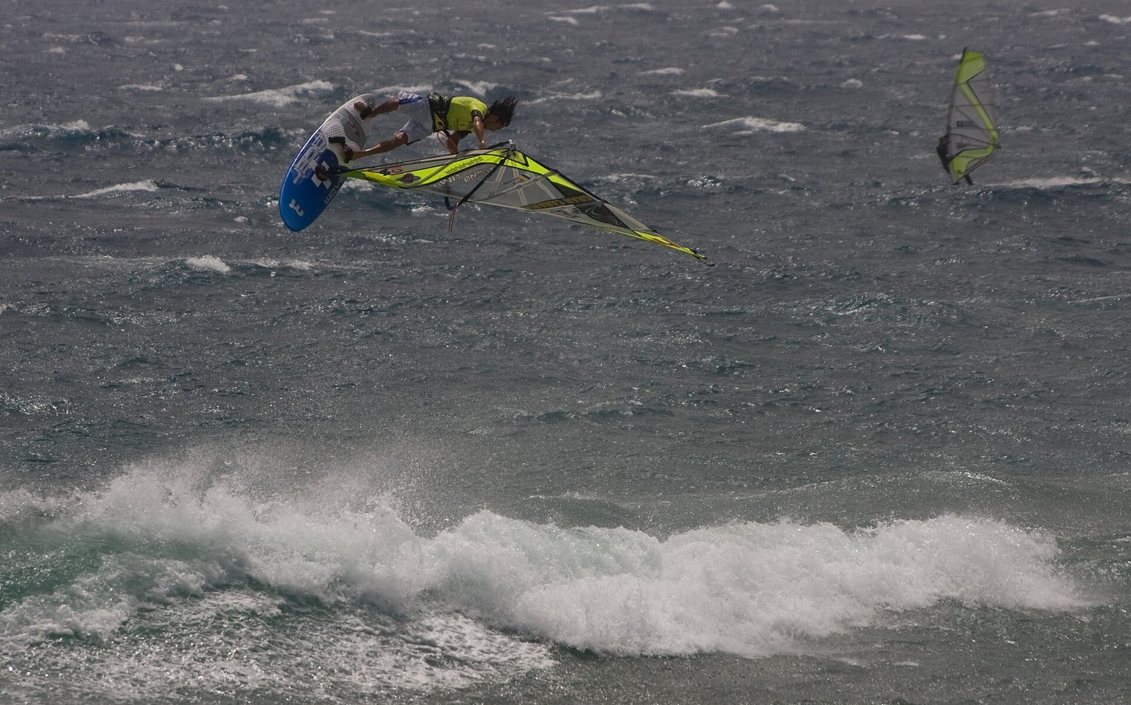 Wingfoiler springt bei starkem Wind über eine Welle vor der Küste Gran Canarias