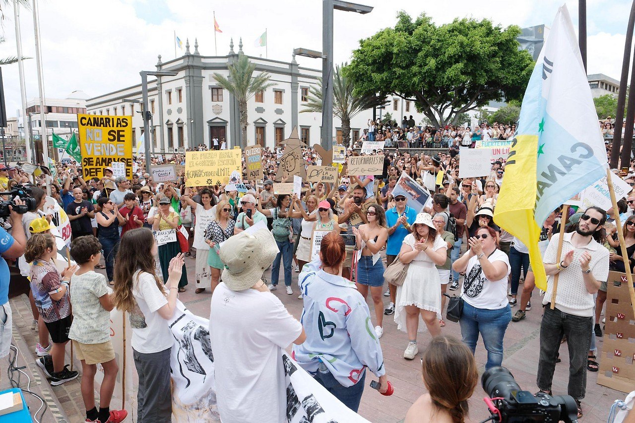 Demonstration gegen Massentourismus auf den Kanaren mit Transparenten und kanarischen Flaggen