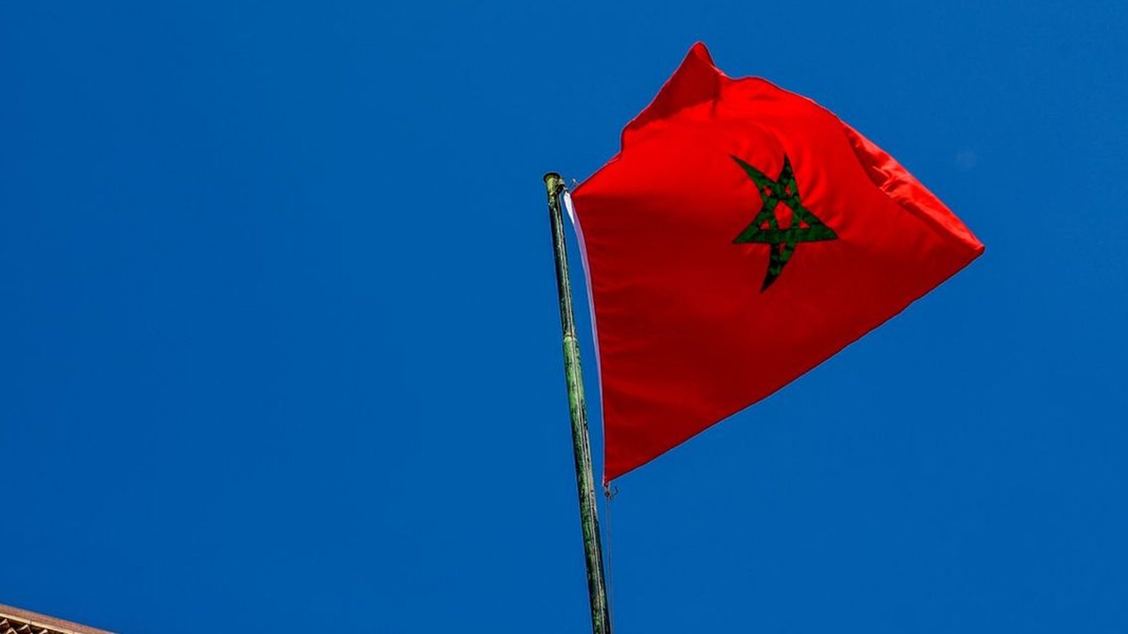 Bandiera del Marocco che sventola contro un cielo azzurro sopra un edificio
