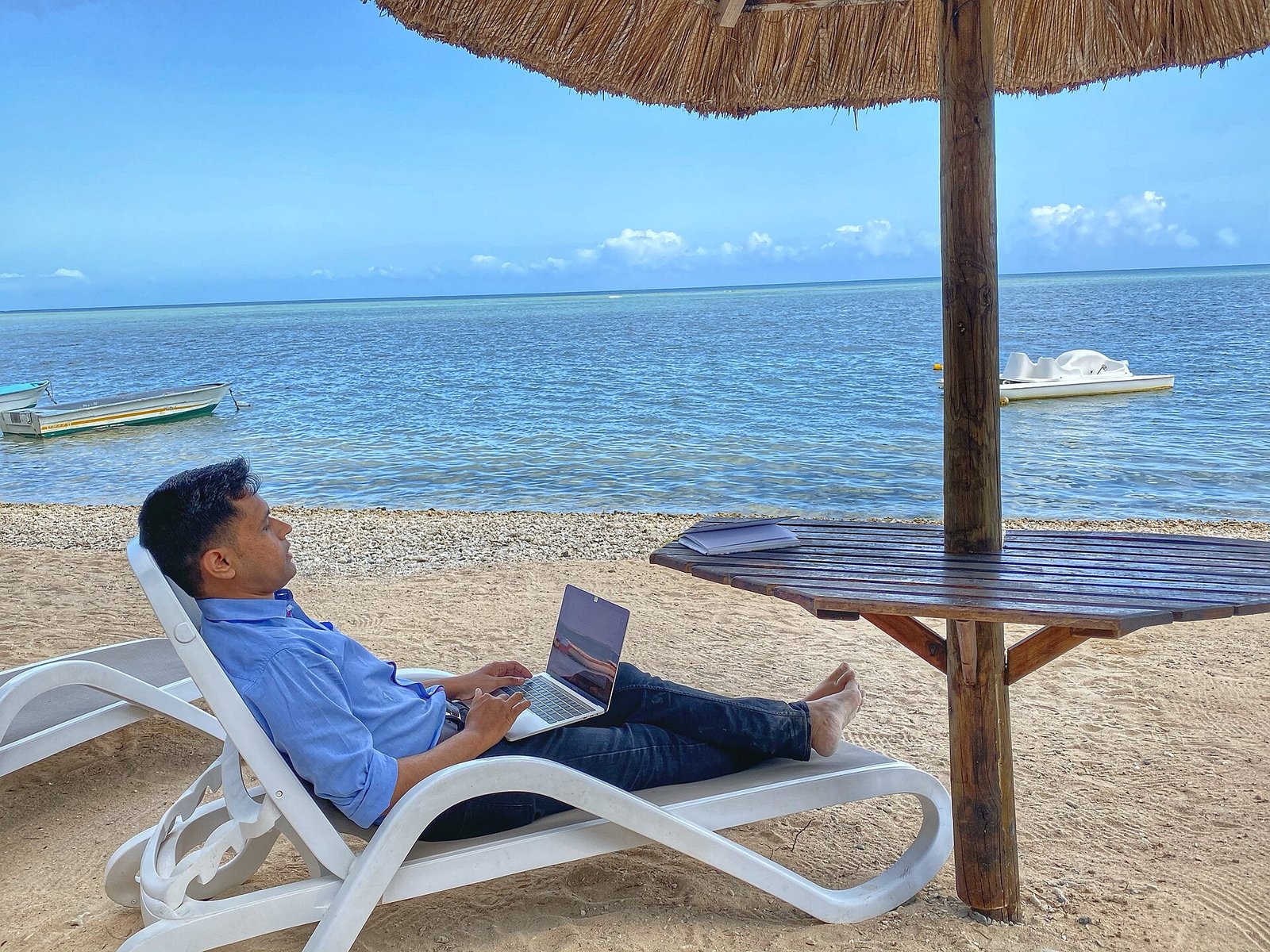 Digital nomad working on a laptop at a shaded beach terrace in the Canary Islands