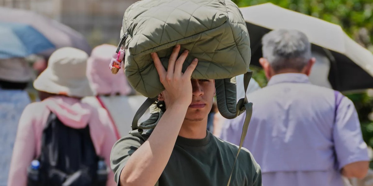 Persona que se protege del sol con un bolso sobre la cabeza
