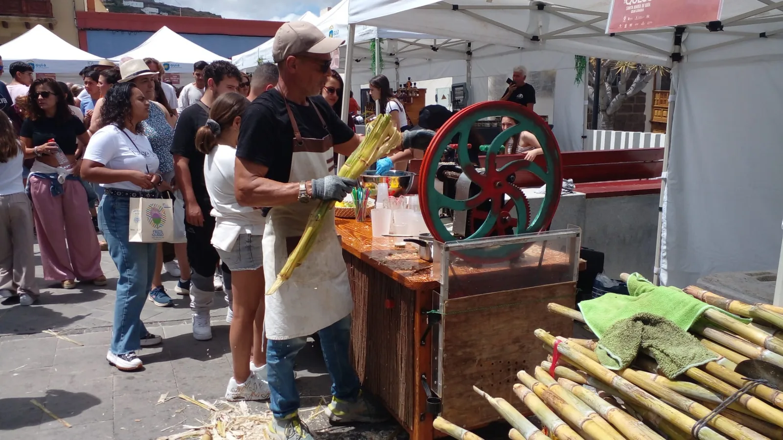 Hombre prensando caña de azúcar en una prensa mecánica con volante verde durante la Fiesta del Queso 2026 en Guía